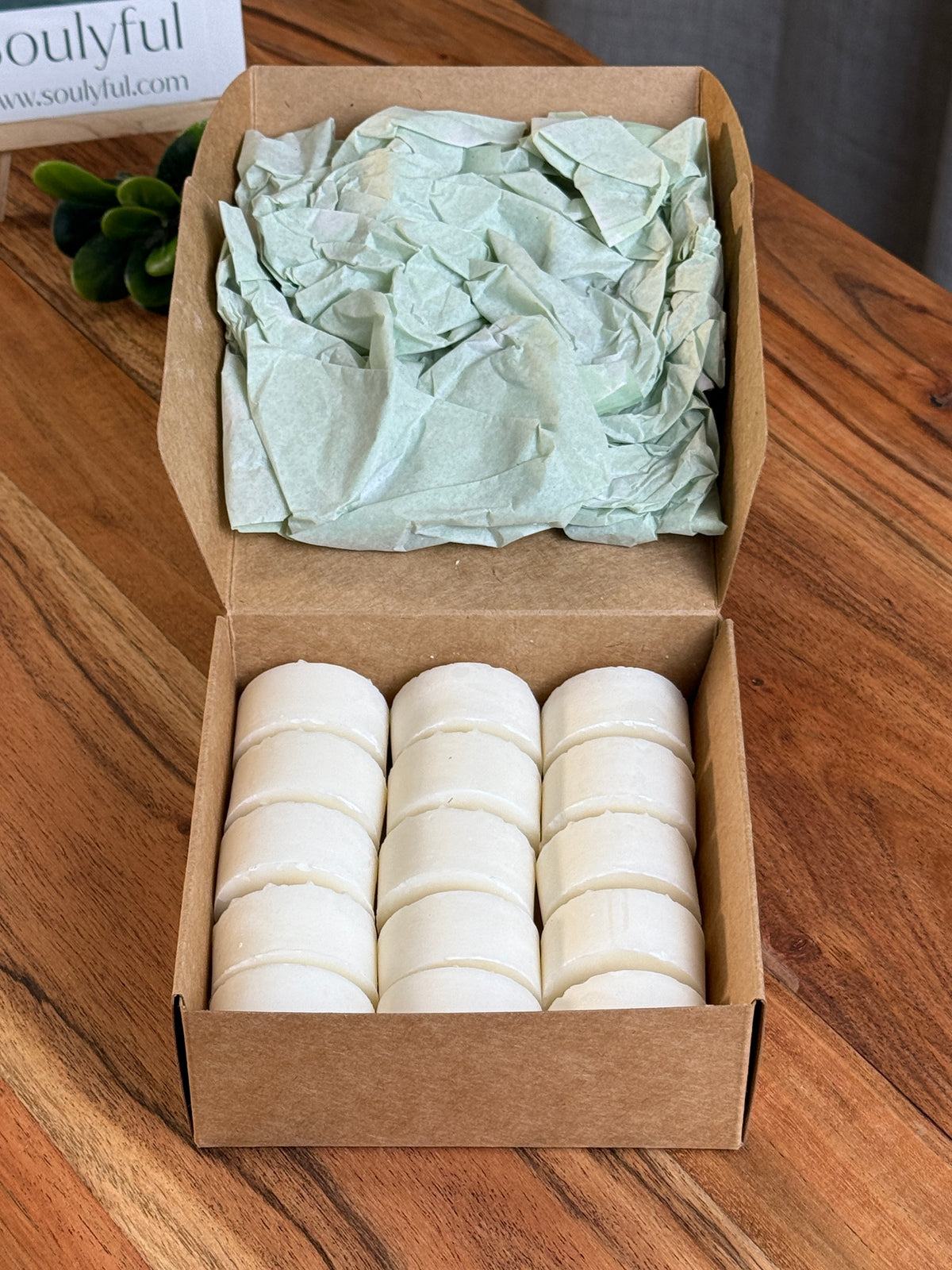Geöffnete Soulyful Box mit 15 weißen Rapswachs-Teelichtern auf einem Holztisch