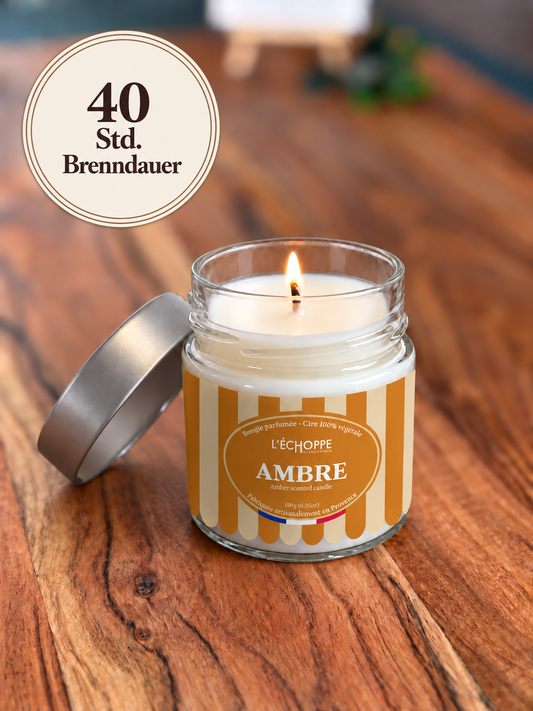 Duftkerze Amber auf Holztisch mit kleiner Flamme und Siegel „40 Std. Brenndauer“