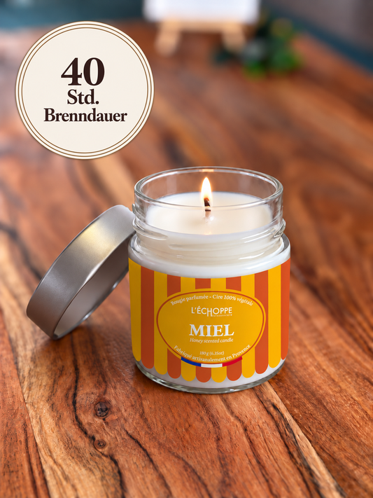 Duftkerze "Honig" auf Holztisch mit kleiner Flamme und Siegel „40 Std. Brenndauer“